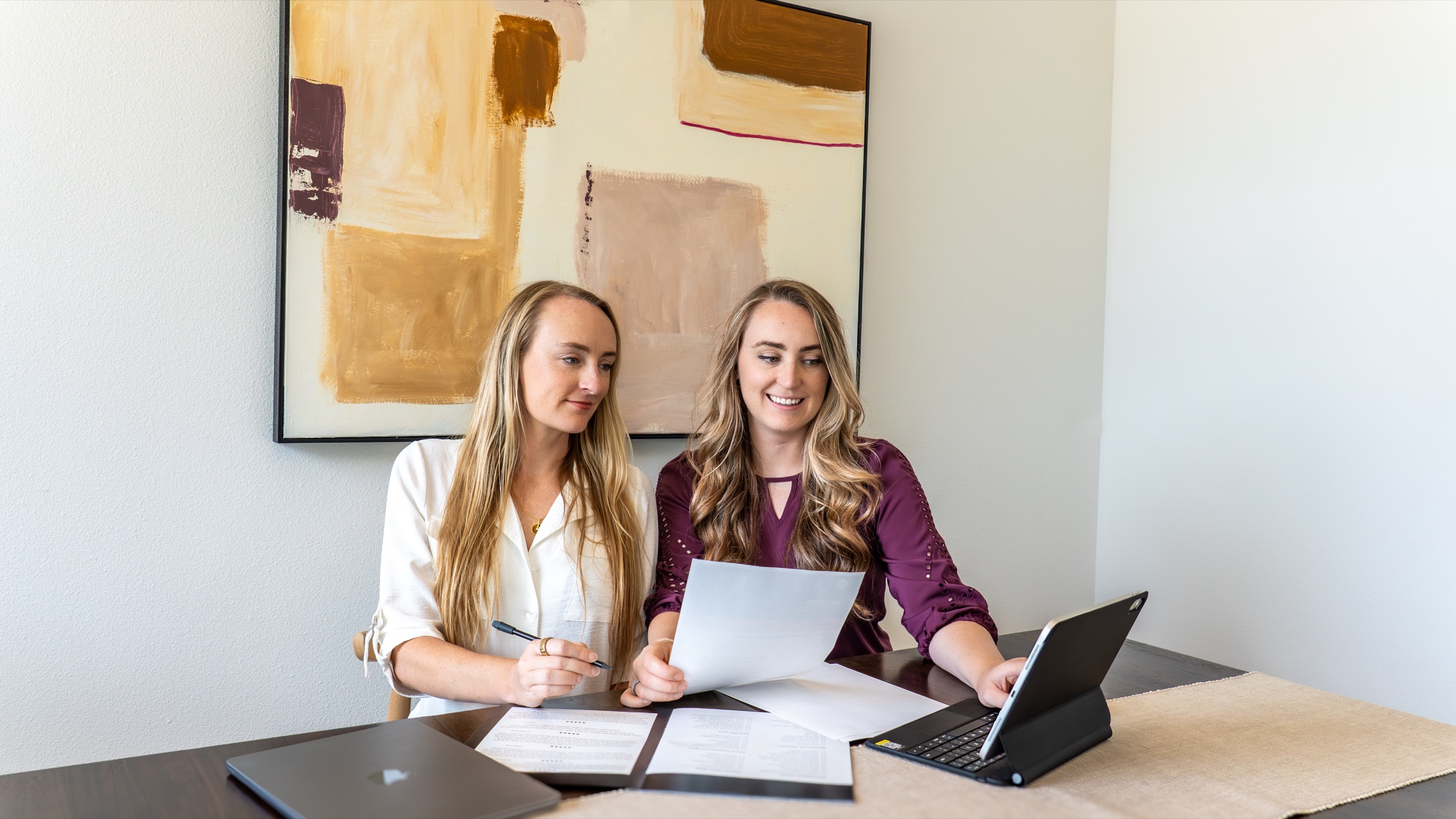 Sarah Machado and Christy Neikirk reviewing billing paperwork together at a table